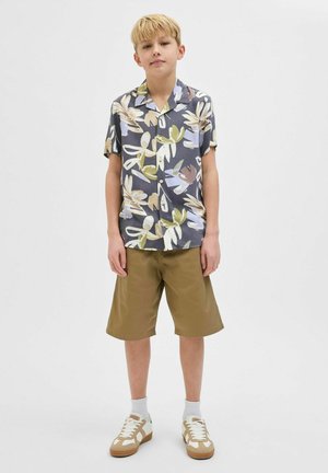 Korte mouwen overhemd met een bloemenpatroon in blauw, groen en beige, gecombineerd met khaki shorts en witte sneakers met tan accenten.
