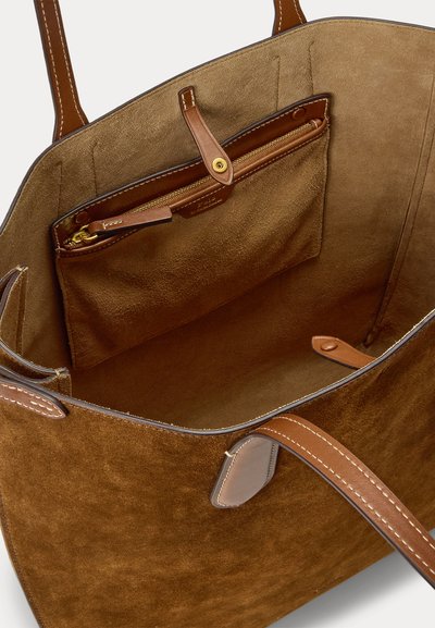 Sac cabas en daim marron avec poignées en cuir, avec une pochette en cuir zippée à l'intérieur, sécurisée par une sangle à bouton-pression.
