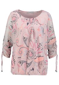 Blusa rosa claro con patrones florales y geométricos, cuello redondo, mangas 3/4, dobladillo elástico y detalles de cordón en las mangas.