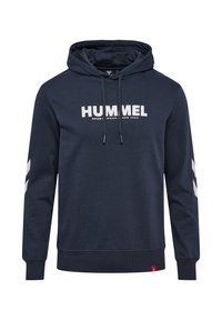 Granatowa bluza z kapturem i sznurkami, biały napis "HUMMEL" i logo na piersi, białe pasy w kształcie szewronu na rękawach, ściągacze na mankietach i u dołu.