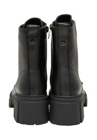 Stivaletti neri alla caviglia in pelle testurizzata, con suola piatta chunky e zip sul retro. Presentano un marchio in rilievo sul tirante.