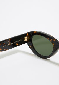 Gafas de sol carey con lentes verdes. Forma de ojo de gato, fabricadas en Italia, con detalles en dorado y medidas grabadas en la patilla.