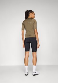 Olivengrønn kortermet sykkeltrøye med et tettsittende design og merket "Isadore" på baksiden, kombinert med svarte sykkelshorts.