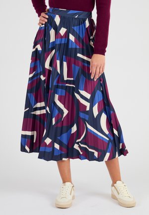 Plisse midi rok in marineblauw, met abstracte patronen in bordeauxrood, blauw en crème. Gecombineerd met lichtgekleurde sneakers.