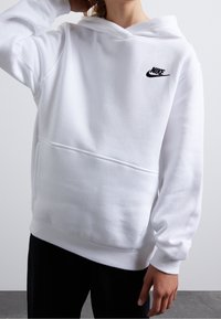 Witte Nike hoodie van zacht materiaal met een frontzak, ribgebreide manchetten en onderrand, met een zwart Nike-logo op de linkerborst.