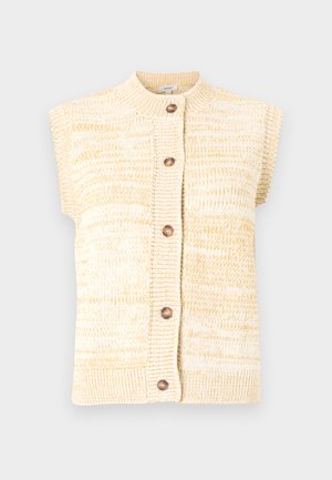 Αμάνικο πλεκτό ζακέτα σε αποχρώσεις κρεμ και μπεζ με στρογγυλή λαιμόκοψη και πέντε ξύλινα κουμπιά κατά μήκος του μπροστινού μέρους.