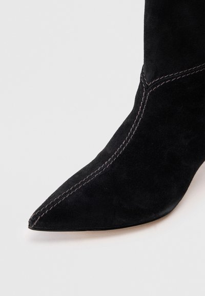 Μαύρη σουέτ ανακορδιέρα με μυτερή μύτη, χαρακτηρισμένη από αντίθετο ανοιχτό ραβδισμό και λεία υφή.