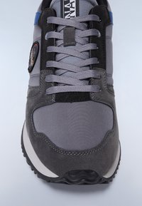 Szare sneakersy z połączenia zamszu i tkaniny, z okrągłym noskiem, wyściółką na języku i teksturowaną gumową podeszwą. Widoczne niebieskie i czarne akcenty.