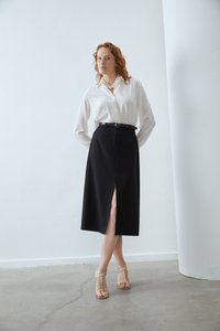 Biela blúzka s dlhými rukávmi, čierna midi sukňa s predným rozparkom a zlaté sandále na opätku. Hladké textúry, elegantný dizajn a prispôsobený strih.