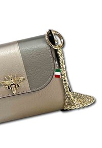 Beige en grijze leren handtas met een gouden bij-embleem, gouden kettingband en een klein Italiaans vlaggetje. Soepele textuur met gestikte accenten.