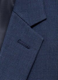 Marinblå blazer i ett strukturerat, vävt tyg. Har en notch-lapel och en enkel knapphål på vänster sida.