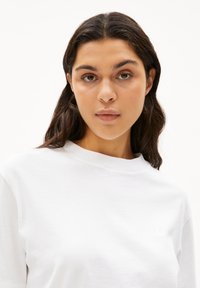 Vit sweatshirt i bomull med rund halsringning och korta ärmar. Har en subtil logotyp broderad på v änster sida. Slät textur.