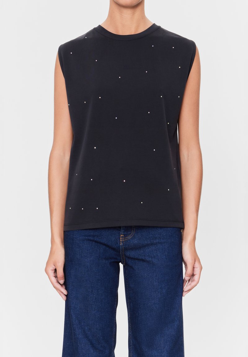 Zwarte mouwloze top met een ronde halslijn, versierd met verspreide kleine, glanzende accenten. Gecombineerd met blauwe spijkerbroek met een relaxed fit.