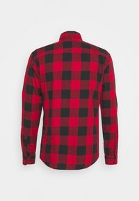Camicia in flanella a quadri rossi e neri con maniche lunghe, colletto e polsini con bottone. Il motivo presenta grandi quadrati alternati.