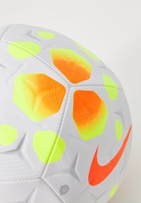 Fotball med hvit overflate, prydet med neongule og oransje heksagonale mønstre, strukturert design og en iøynefallende oransje Nike-logo.