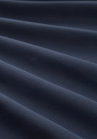 Ciemnoniebieska tkanina charakteryzująca się miękką, gładką teksturą z łagodnymi falami, podkreślająca płynny fason materiału oraz jego równomierną głębokość.