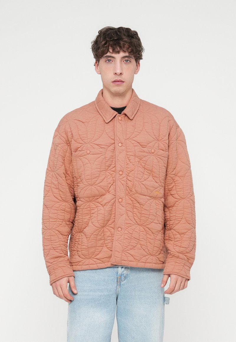 Πανωφόρι με καπιτονέ ύφασμα σε απαλό ροδακινί χρώμα, με γιακά, κουμπιά με κούμπωμα και δύο εμπρόσθιες τσέπες με υφή που μοιάζει με φύλλα.