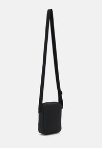 Borsa a tracolla nera di forma rettangolare, realizzata in materiale liscio, con tracolla regolabile e scomparto principale con zip.