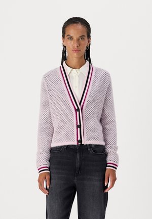 Light pink knitted cardigan with a textured pattern, black buttons, and contrasting striped cuffs. Paired with dark jeans and a white shirt.