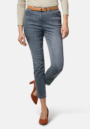 Grijze denim jeans met een middenhoge taille, vijf-pocket ontwerp en een tan leren riem. Draagt bijpassende bruine suède hoge hakken.