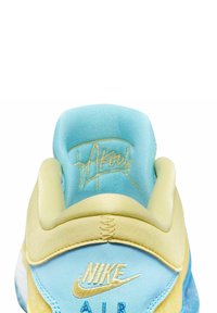 Scarpa Nike Air con tomaia azzurro chiaro e accenti gialli. Il tallone presenta un design testurizzato e un logo ricamato sul lato.