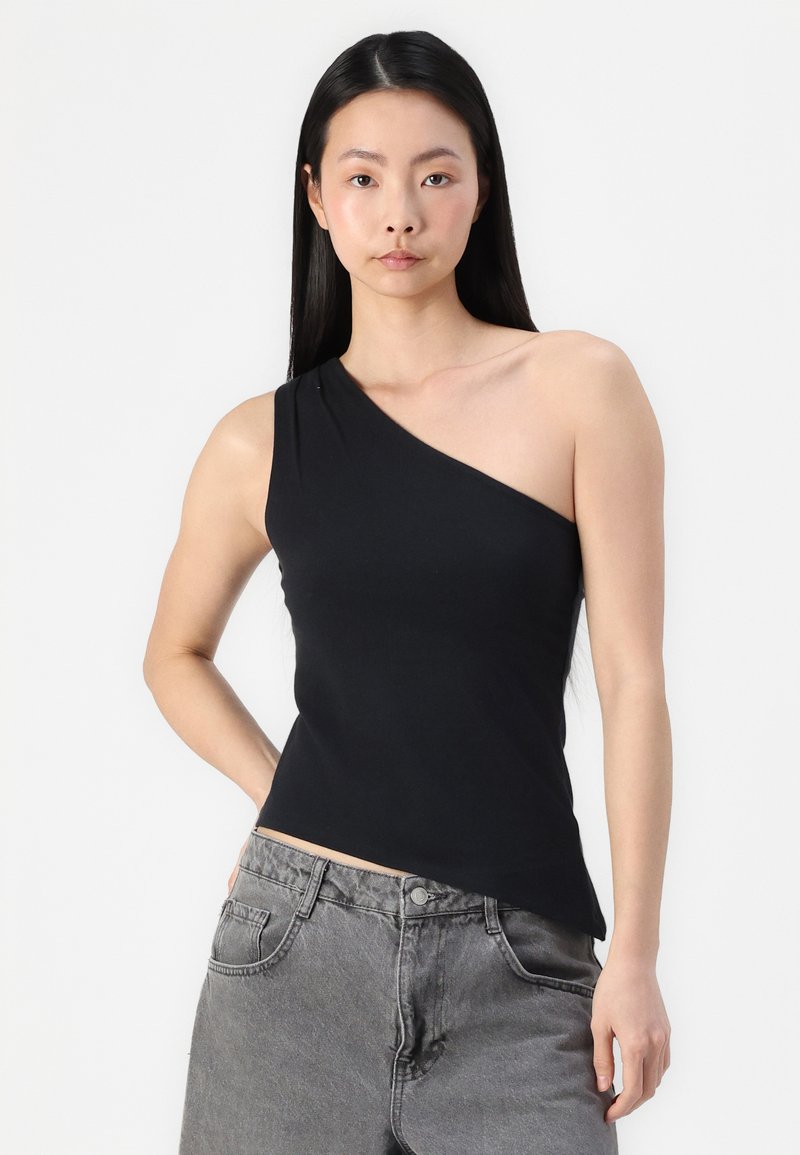 Schwarzes Ein-Schulter-Top aus elastischem Stoff, taillierter Schnitt, glatte Textur, kombiniert mit hochgeschnittenen grauen Denim-Jeans.