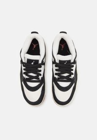 Zapatillas en blanco y negro con una parte superior de ante y malla, cordones prominentes, cuello acolchado y detalles del logotipo en rojo en la lengüeta y la plantilla.