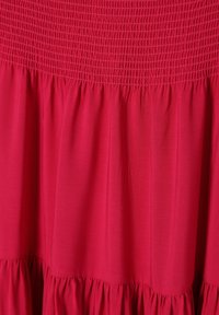 Felle rode rok van geplooide stof met gestikte elastische tailleband en gelaagde ruches aan de zoom.