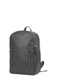 Svart läderryggsäck med rundad form, framfickan med dragkedja, handtag ovanpå och justerbara remmar. Slät yta, minimalistisk design.