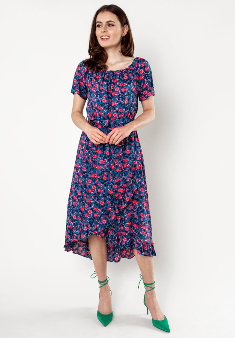 Bloemen midi-jurk in marineblauw met roze bloemen, korte mouwen en een gerimpelde zoom. Gecombineerd met groene sandaaltjes. Lichte stof.