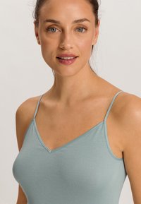 Camisola blu chiaro con spalline sottili, design a V, realizzata in tessuto morbido ed elasticizzato, che mette in risalto una superficie liscia e una silhouette aderente.