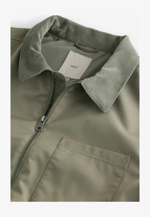 Khakijacke mit Reißverschluss, Cordkragen und einer Brusttasche, aus glattem Material mit matter Oberfläche.