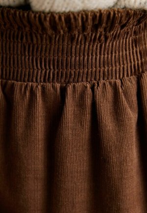 Brązowa spódnica sztruksowa z marszczoną gumką w pasie i marszczoną teksturą, podkreślająca pionowe prążkowanie i miękki materiał.