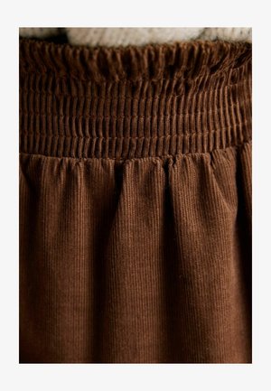 Ruskea corduroy-hame, jossa on smokattu vyötärönauha ja kerätty pintakuvio, korostaen pystysuuntaista ribikuviointia ja pehmeää kangasta.