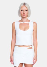 Biała dopasowana crop top z okrągłym dekoltem i ramiączkami z metalowym zapięciem. Połączony z dopasowaną białą mini spódnicą typu wrap.