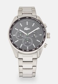 Montre en acier inoxydable argenté avec un cadran noir, trois sous-cadrans et des accents verts. Comprend une lunette tachymétrique et un bracelet en métal linké.