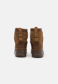 Brune Suede ankelboots med en luksuriøs inderside, med en kontrastfarvet gummisål, trækkroge og UGG-branding på bagsiden.