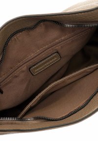 Brown leather handbag interior with a textured finish, featuring a zip pocket and two open compartments, all lined in a smooth fabric.