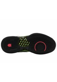Semelle de chaussure de sport noir et vert avec une surface en caoutchouc texturé, arborant un motif géométrique et un accent circulaire rose. Design non-marquante.