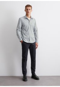 Light blue floral shirt with a button-down collar, paired with dark navy slim-fit pants and black shoes. Smooth fabric texture.