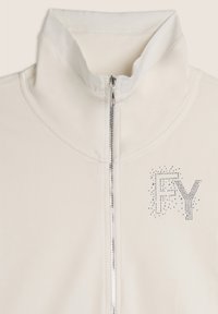 Giacca bianca con zip e colletto alto. Presenta le lettere "FY" decorate con strass. Texture morbida con un finish liscio.
