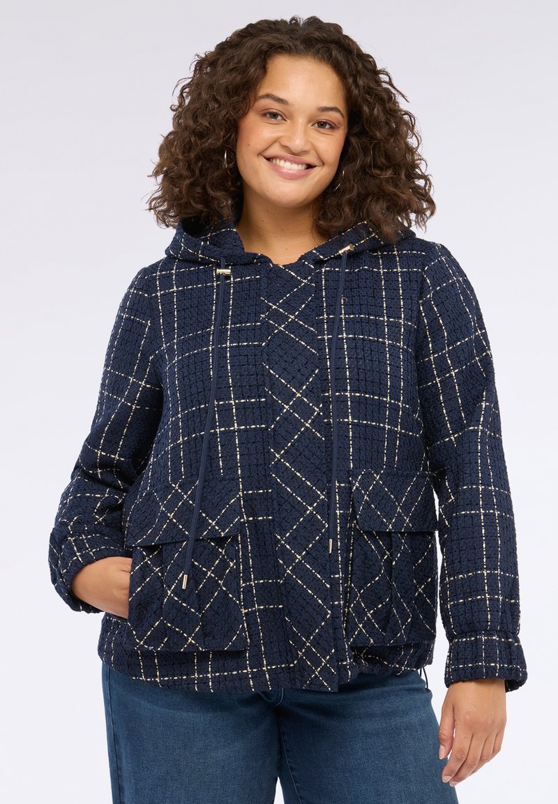 Mörkblå huvajacka med quiltad textur, prydd med rutigt mönster i vita och gyllene trådar, samt två framfickor.