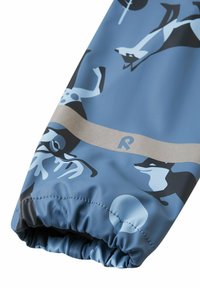 Tessuto blu con finitura lucida che presenta un motivo di fauna selvatica in blu scuro e nero. Polsino elastico con una banda di accento grigia all'apertura.