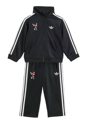 Tuta Adidas nera con strisce bianche, giacca con zip, pantaloni e ricamo di Topolino che gioca a calcio sulla giacca e sui pantaloni.