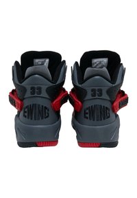 Vysoké sportovní tenisky z šedé kůže s červenými akcenty. Mají nastavitelné pásky, texturované povrchy a značkové detaily na patě.