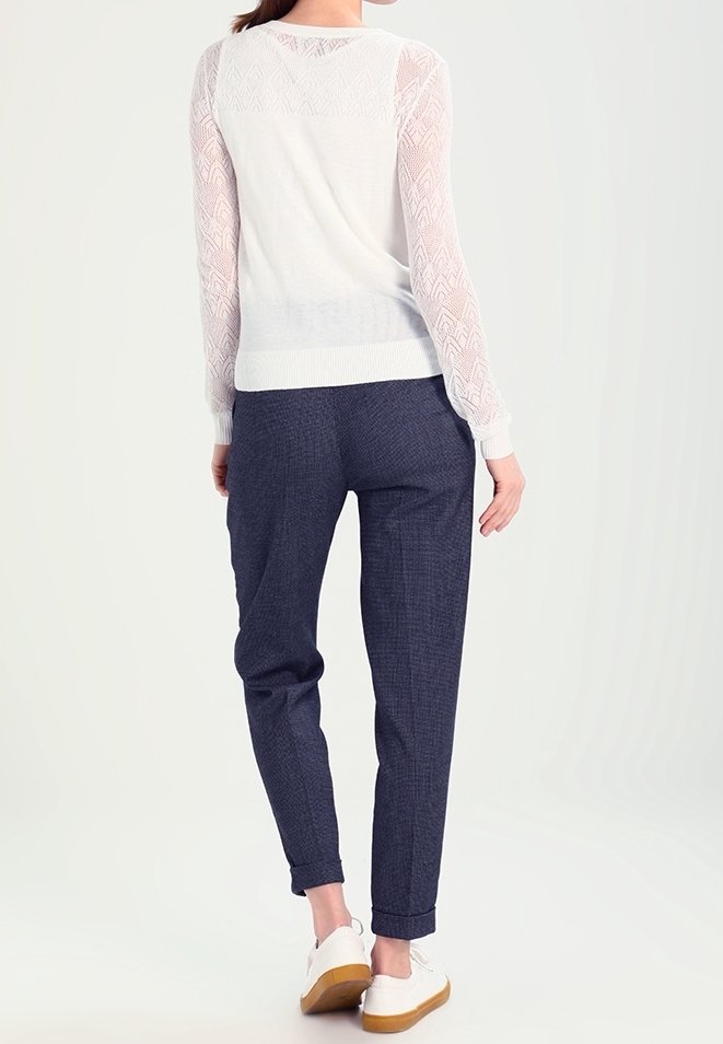 Vit stickad tröja med spetsärmar, kombinerad med marinblå rutiga byxor och vita sneakers. Enkel, avslappnad passform.