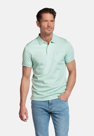 Lichtgroene polo met kraag, korte mouwen en een borstzak. Gemaakt van een zachte stof met een relaxte pasvorm. Gedragen met lichtblauwe jeans.
