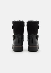 Botas de invierno negras con parte superior de ante, forro de piel sintética, detalle de hebilla y tacón de cuero texturizado. Cremallera en el lado exterior.