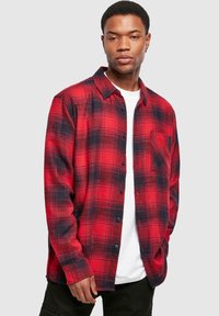 Chemise en flanelle à carreaux rouges et noirs avec manches longues, devant boutonné et poche poitrine. Fabriquée en tissu doux avec une coupe décontractée.