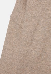 Beige sweatshirtstof med en blød tekstur, der har en synlig lomme søm og et let meleret mønster. Glat, afslappet stil.